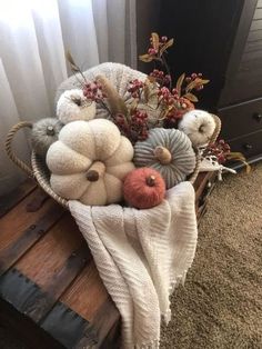 a basket filled with white pumpkins on top of a wooden table next to a window