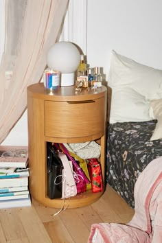 there is a small round table with many items on it next to the bed and pillows