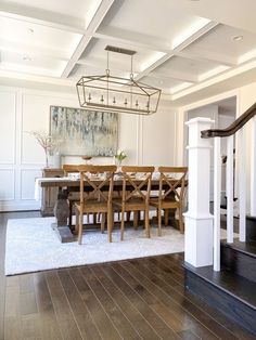 a dining room table with chairs and a chandelier hanging from it's ceiling