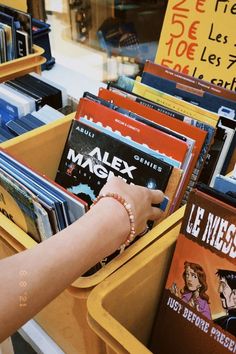 a person is picking up some books from a bin