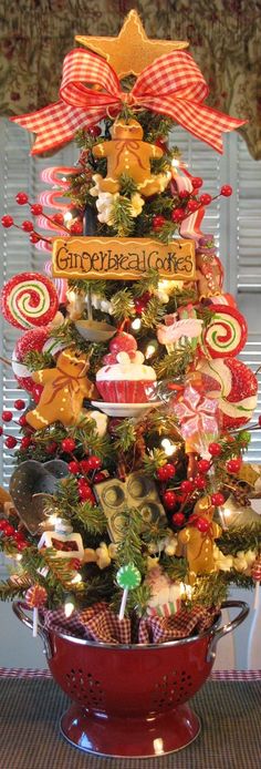 a christmas tree decorated with candy canes and bows in a red colander bowl