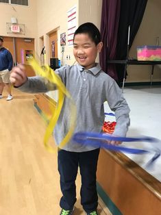 a young boy is holding some yellow and blue streamers in his hands while standing on the floor