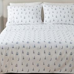 a white bed with blue sailboats on it and two pillow cases sitting next to each other