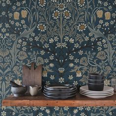 plates and bowls are sitting on a shelf in front of a wallpaper