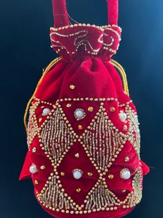 a red bag with gold beading and pearls on the front, hanging from a hook