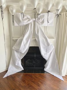 white balloons are tied to the back of a fireplace