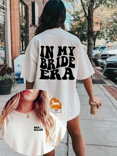 a woman walking down the street wearing a t - shirt that says in my bride era