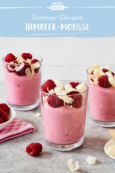 three desserts with raspberries and almonds in small glass cups on a table