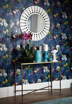 a table with flowers and vases on it in front of a wallpapered background