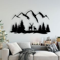 a living room with a white couch and christmas tree in the foreground, two deer silhouettes on a mountain