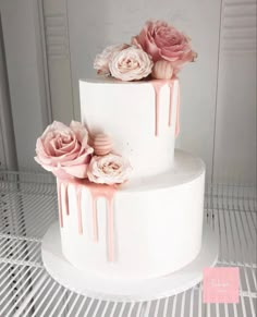 a white cake with pink icing and flowers on top is sitting on a rack