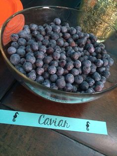 a bowl filled with blueberries sitting on top of a table next to a sign