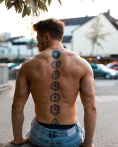 a man sitting on the ground with his back to the camera and tattoos on his body