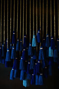 blue and gold tassels hanging from strings in the dark, close up view