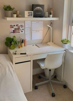 a white desk sitting under a window next to a bed