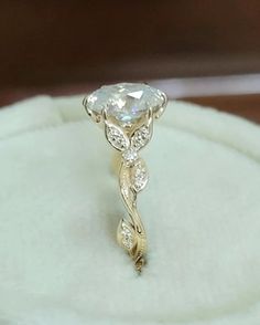 an engagement ring sitting on top of a white cloth covered box with a diamond in the center