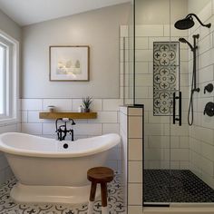 a white bath tub sitting next to a window in a bathroom with black and white tile