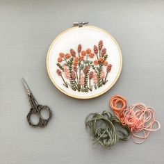 a pair of scissors and some thread are on the table next to an embroidery kit