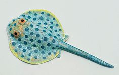 a paper plate with a blue and yellow fish on it's side, sitting on a white surface