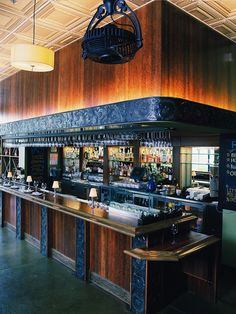 an empty bar with lots of bottles on the counter and lights hanging from the ceiling