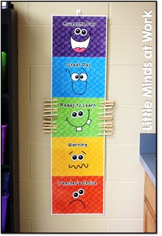 a bulletin board with five different colors and faces on it, hanging from the wall