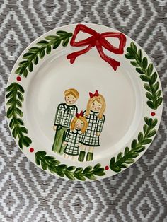 a white plate with a red bow on the top and two people painted on it