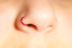 a close up view of the side of a person's ear with a pink nose ring