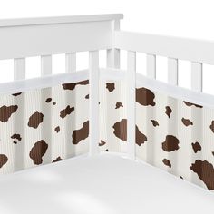 a white crib with brown and white cow print