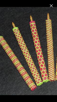 six crocheted pencils are lined up on a black surface