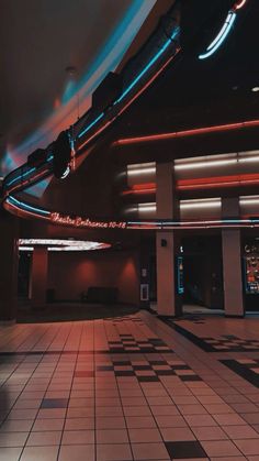 an empty room with tiled floors and neon lights