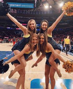 three cheerleaders posing for a photo on the basketball court with their pom poms