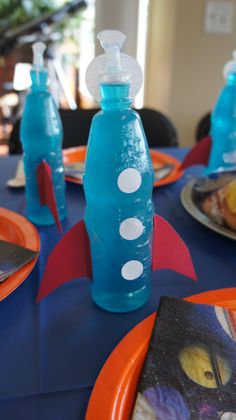 a blue bottle with white dots on it sitting on top of a table next to plates and utensils