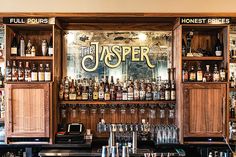 a bar with liquor bottles and glasses on the back wall, behind it is a sign that reads the jumper