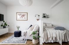 a white room with a bed, couch and television on the wall next to it