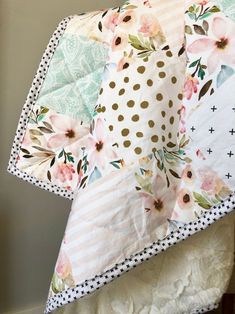 an unmade quilt on top of a bed with polka dots and pink flowers in the center