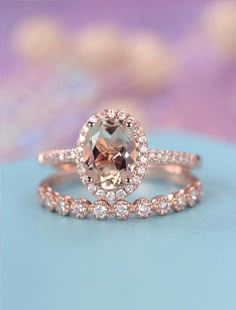 an engagement ring with a large morganite surrounded by smaller diamonds on a blue surface