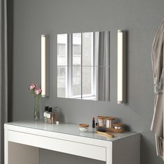 a bathroom vanity with a mirror and lights on the wall above it, along with other items