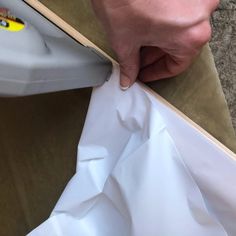 a person is cutting paper with a large iron on top of the sheeting paper