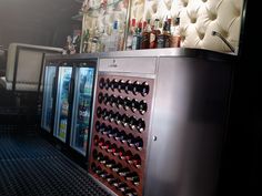 an empty wine cooler in the middle of a room filled with bottles and liquors