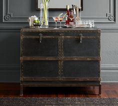 an old trunk is filled with liquor bottles and glasses on the sideboard in front of a mirror