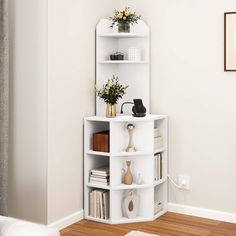 a white corner shelf with books and vases on it in the corner of a room