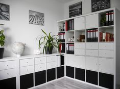 a white and black room with bookshelves and plants