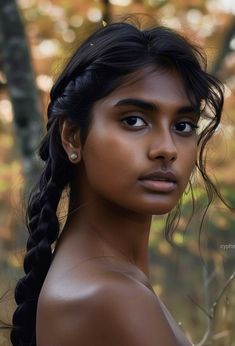 a woman with braids is posing for a photo in front of trees and leaves