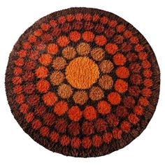 an orange and brown circular rug on a white surface with circles in the center,