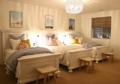 two twin beds in a bedroom with white walls and beige carpeted flooring, along with pictures on the wall