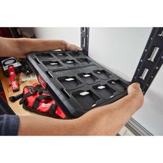 a man holding a tool tray with tools in it