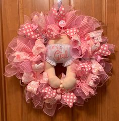 a pink and white wreath with a teddy bear on it's front door hanger