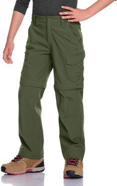 a man standing with his hands on his hips wearing green pants and hiking shoes,