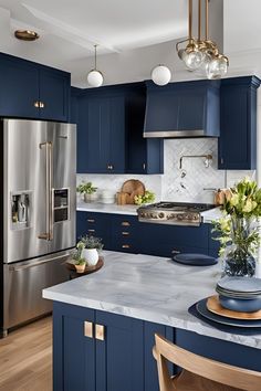 a kitchen with blue cabinets and marble counter tops, an island in front of the refrigerator