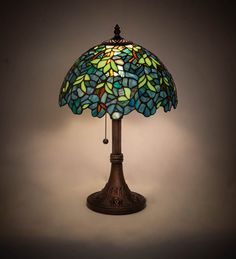 a stained glass lamp on a table with a white wall behind it and a dark background